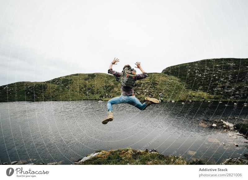 Backpacker jumping on landscape Man backpacker Jump Freedom Landscape Vacation & Travel Mountain Happiness Lakeside Nature above ground Movement Rock