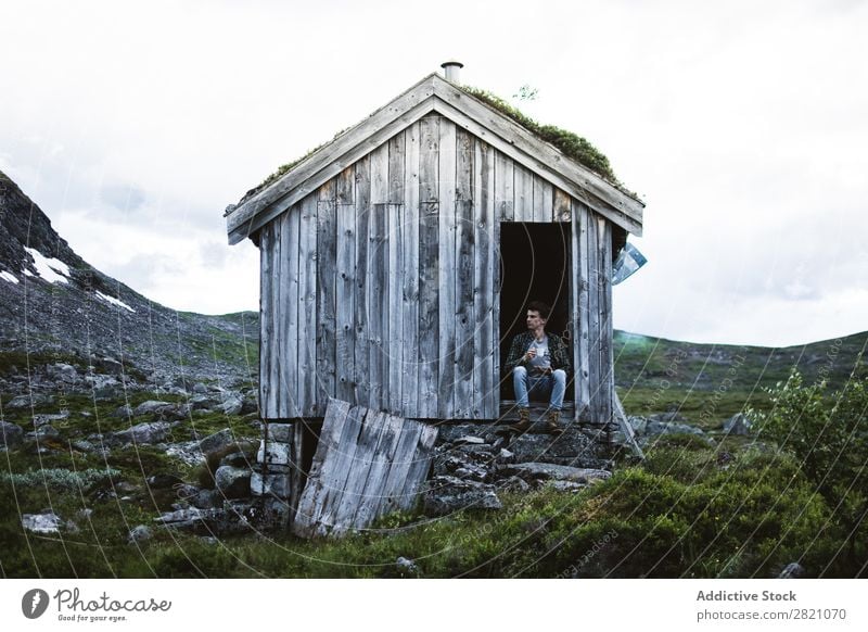 Man sitting in a old house in nature Hut Mountain Remote tranquil terrain bending House (Residential Structure) but Nature Landscape Peaceful Building Exterior