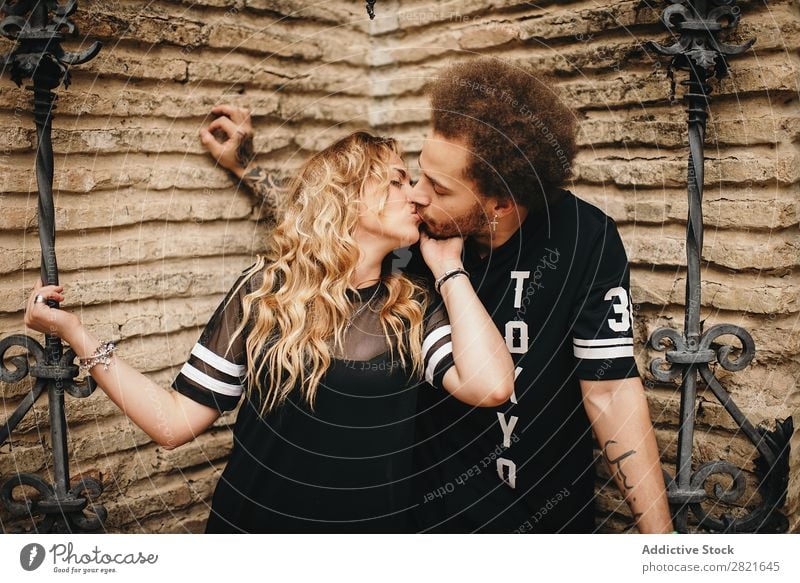 Kissing couple at stone wall with metal decorated bars Couple Hipster Love Relationship tender Passion Blonde Hair and hairstyles Beard Man Woman Curly hair