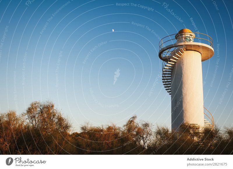 Lighthouse over bright blue sky with half moon Sky Moon Sunbeam Tree Building White Stairs Horizontal Background picture Blue Clear Evening Sunset Deserted