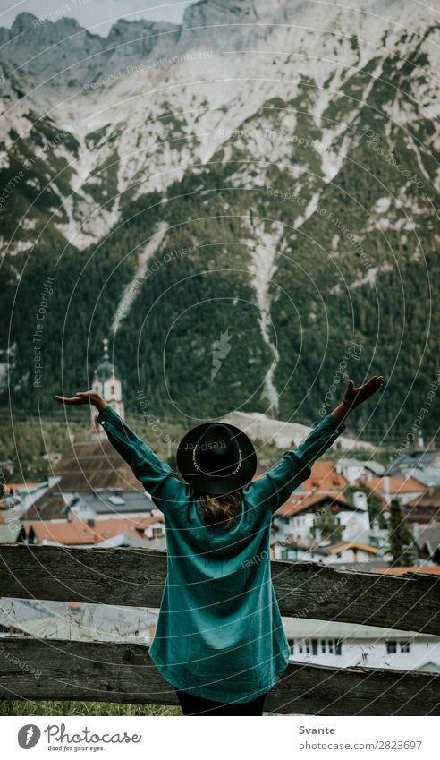 Woman standing in front of mountain town with outstretched arms Lifestyle Joy Vacation & Travel Tourism Adventure Summer Mountain Hiking Feminine Young woman