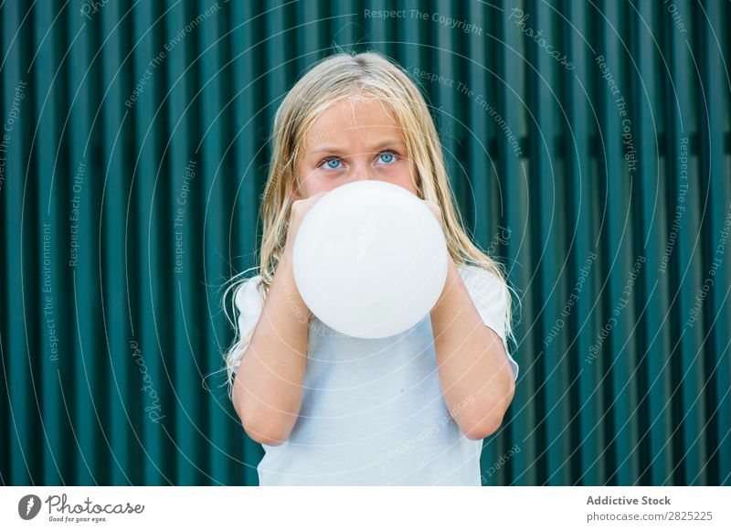 Girl blowing balloon outside Balloon Blow Posture Earnest Unemotional Town Infancy inflating Birthday Youth (Young adults) Portrait photograph Party facial