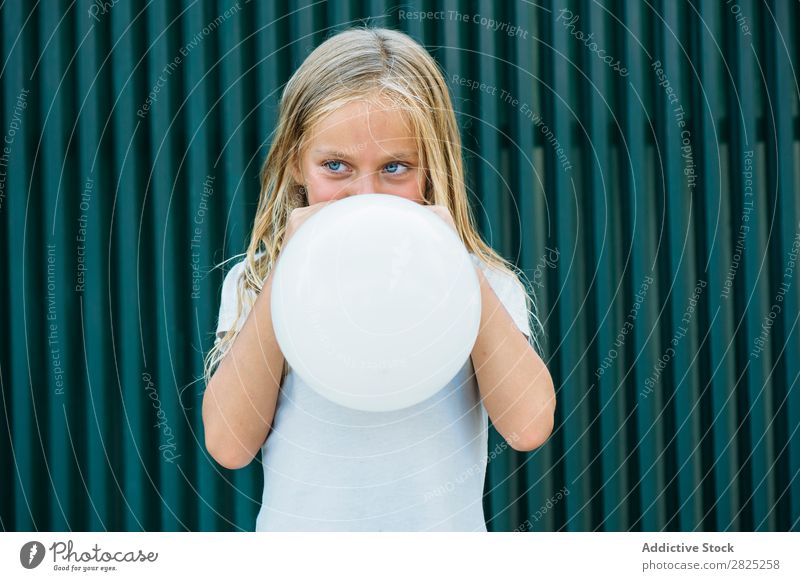 Girl blowing balloon outside Balloon Blow Posture Earnest Unemotional Town Infancy inflating Birthday Youth (Young adults) Portrait photograph Party facial