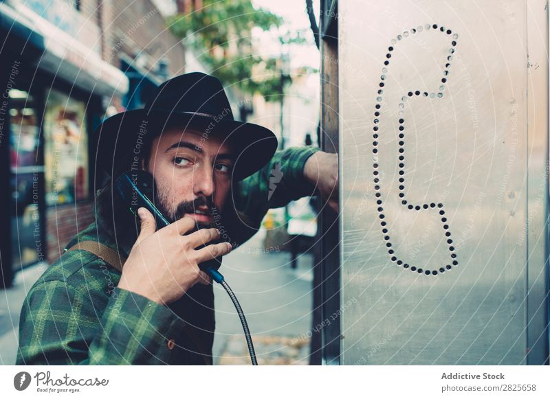 Man wearing hat talking coinbox Self-confident To talk To call someone (telephone) Hat bearded Earnest Street Brutal Beard Human being City Hipster Adults