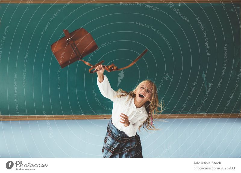 Girl throwing backpack in classroom Classroom Blackboard Joy Backpack Vacation & Travel Happy Cheerful Stand Cute Education School Grade (school level) Student