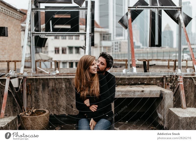 Lovely couple sitting on the rooftop with great city view on bac Couple Cheerful Embrace City Sit Skyline Architecture love story Town Joy Together Happy