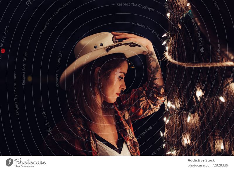 Woman in hat near tree with garland Style stetson cowgirl Hat Youth (Young adults) Beautiful Western American Adults cowbow hat Tattooed Clothing Tree
