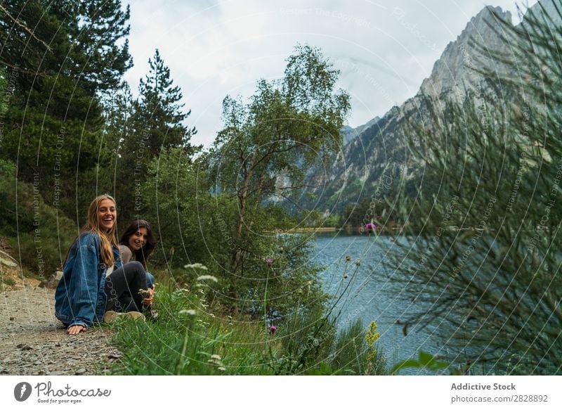 Cheerful women sitting at lake Woman Mountain Smiling Sit Together Happy Laughter Hiking Lake Water Vacation & Travel Adventure Tourist Youth (Young adults)