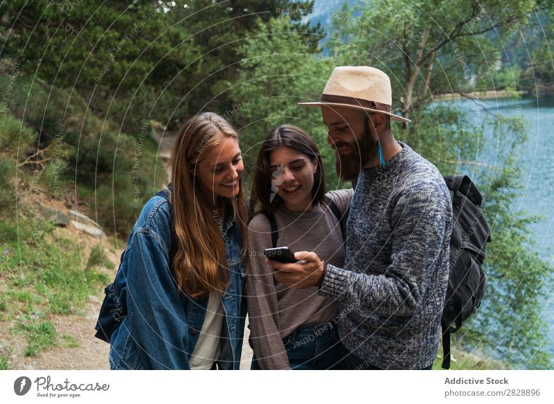 Friends with phone in mountains Woman Man Mountain Walking PDA using browsing Together Smiling Hiking Lake Water Cheerful Happy Vacation & Travel Adventure