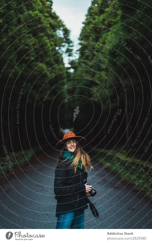 Smiling woman with camera in woods Woman Photographer Forest Green Nature Camera Hat pretty Youth (Young adults) Street Asphalt Environment