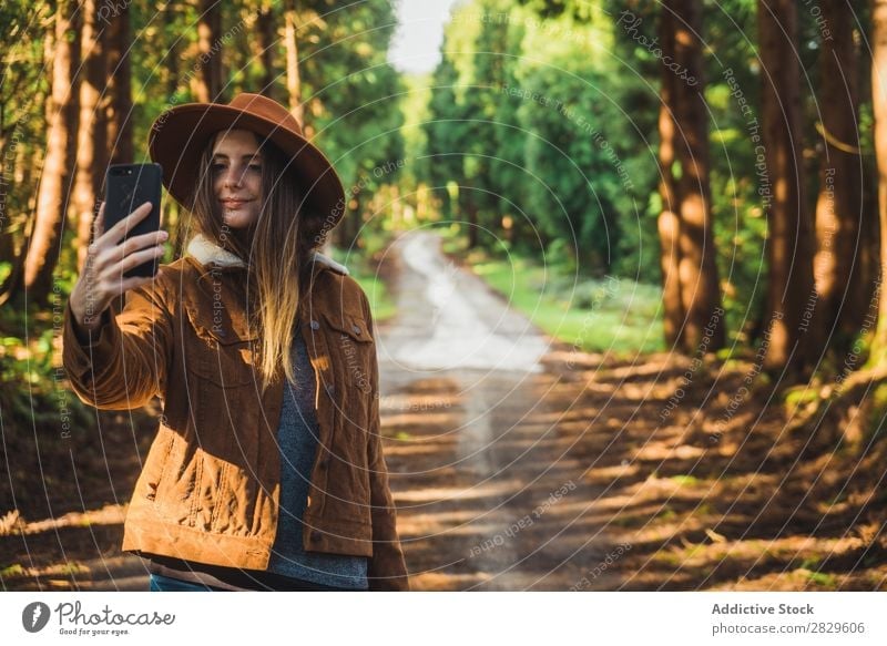 Smiling woman taking selfie in woods Woman Tourist Forest Green Nature Environment Cheerful Happy Selfie PDA Take Shot Hat pretty Natural Seasons Plant Leaf