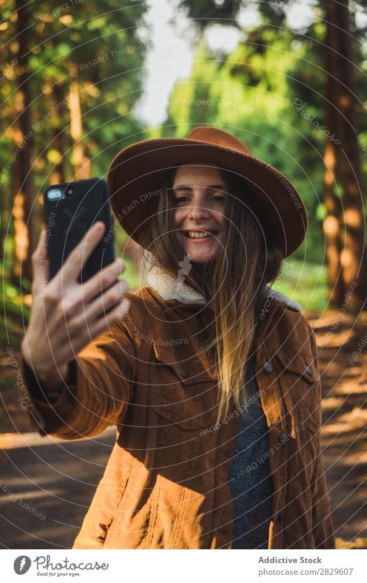 Smiling woman taking selfie in woods Woman Tourist Forest Green Nature Environment Cheerful Happy Selfie PDA Take Shot Hat pretty Natural Seasons Plant Leaf