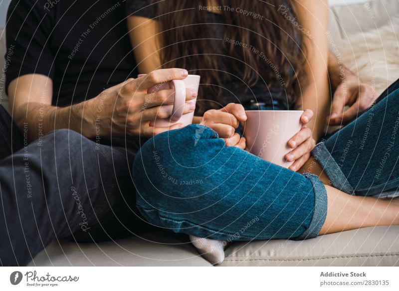 Crop couple with cups Couple Home Together Sit embracing Cup Drinking Beverage Sofa Couch Cozy Human being Happy Love House (Residential Structure) Man Woman