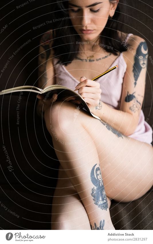 Tattooed woman writing in notebook Woman Home Bed Diary Notebook Easygoing Writing Pen memories Interior shot Lifestyle Adults Sit T-shirt Youth (Young adults)
