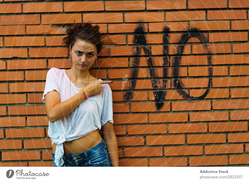 Woman pointing at word on wall Indicate Street forbidden Negative Denial Deserted Town Wall (building) Communication negation rejection Word Grimace Gesture