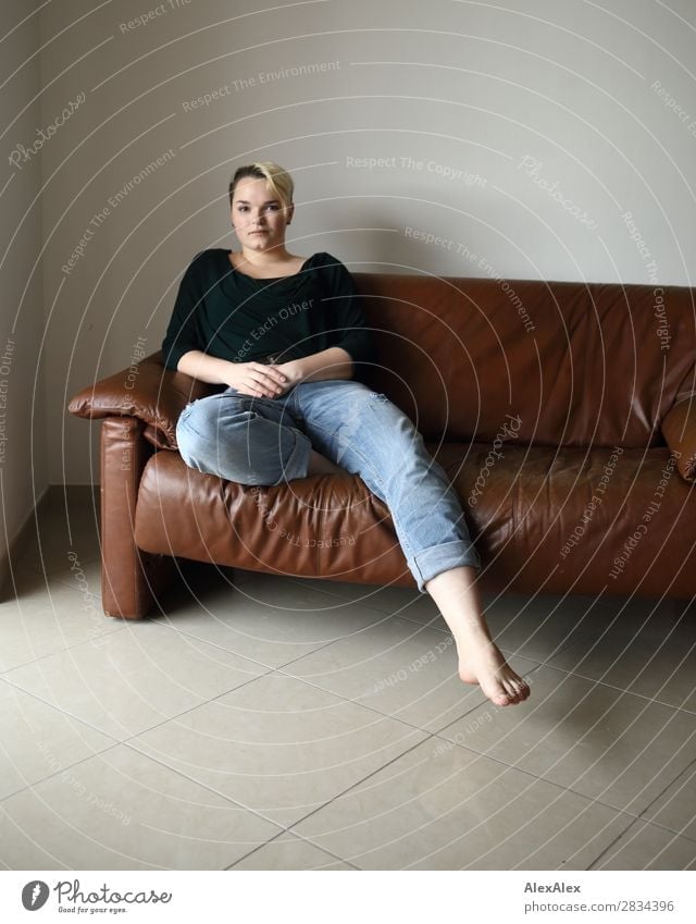 Young woman sits on the couch and sticks out one leg Style Contentment Sofa Room Youth (Young adults) 18 - 30 years Adults Jeans Piercing Barefoot Blonde