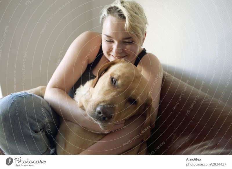 Young woman smiles and holds blond Labrador in her arms Style Joy pretty Harmonious Well-being Flat (apartment) Youth (Young adults) 18 - 30 years Adults Jeans