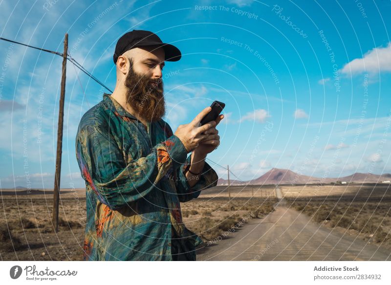 Man with phone on rural road Tourist Mountain Clouds Field PDA using browsing bearded Nature Landscape Natural Rock Stone Lanzarote Spain Vantage point