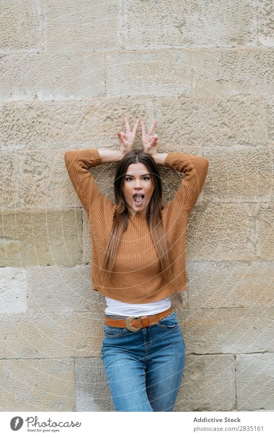 Woman with mouth opened posing near wall Gesture two fingers Happy Brick Wall (building) Human being Caucasian Youth (Young adults) Beautiful romantic Adults