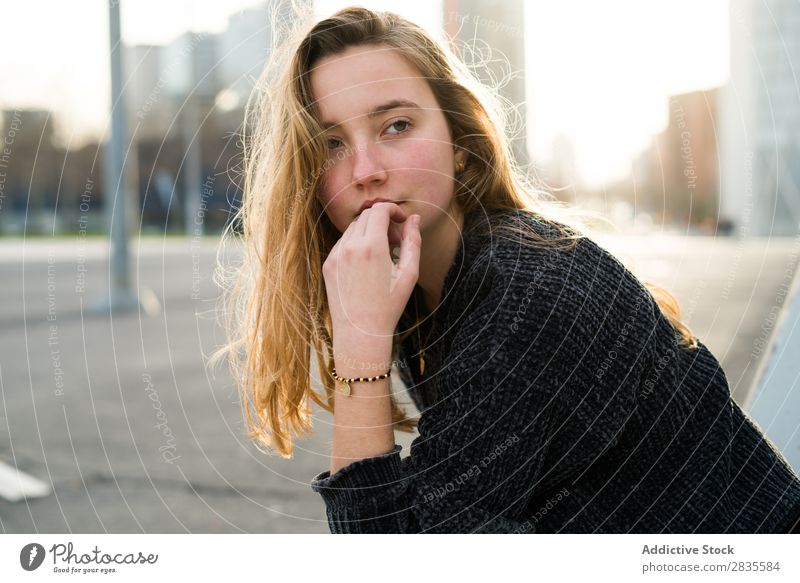 Dreamy girl looking away Woman Sit Considerate Pensive Looking away Touch Lips City Town Street pretty Youth (Young adults) Beautiful Sweater Easygoing Girl
