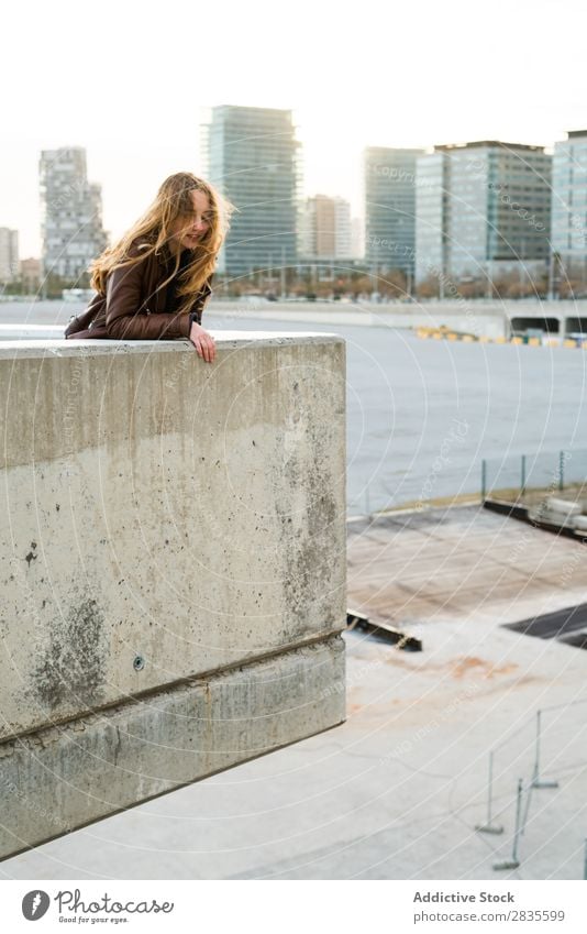 Woman leaning on a block Concrete Block Lean Town Street City Building Dream Smiling Flying Hair Considerate Pensive pretty Youth (Young adults) Beautiful