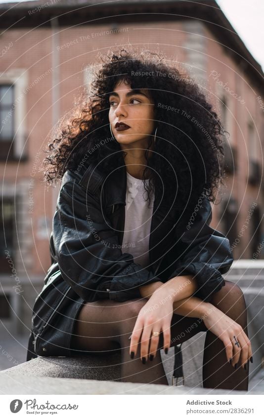 Pretty woman sitting on fence Woman Attractive City fashionable Curly Brunette Jacket Fence Fashion Youth (Young adults) Beautiful pretty Street Model Style