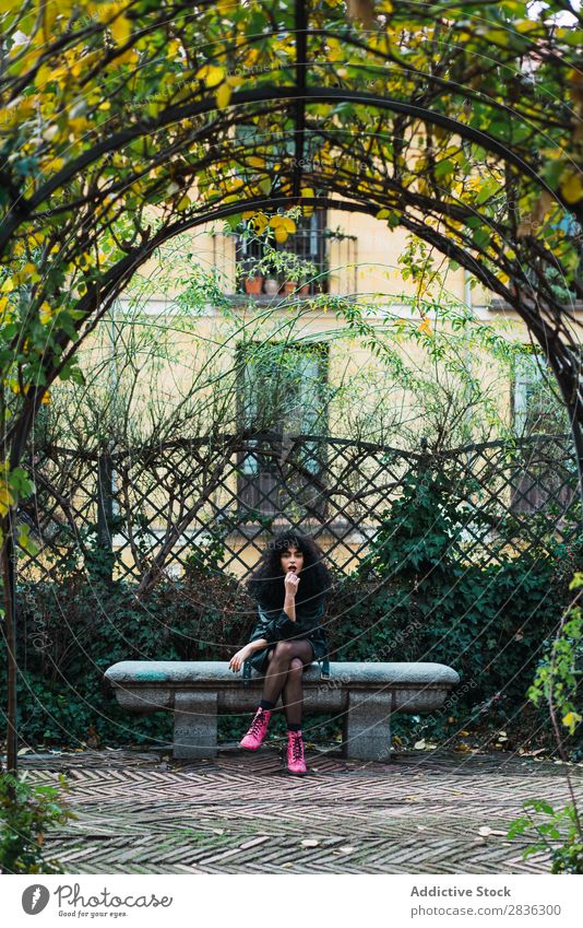 Woman on fence in park Attractive City fashionable Curly Fence Park Brunette Jacket Fashion Youth (Young adults) Beautiful pretty Street Model Style Hair