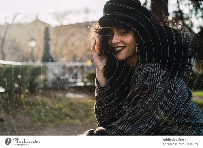 Young stylish woman sitting in city Woman Attractive City fashionable Curly Brunette Coat Hat Sit Fence Vantage point Fashion Youth (Young adults) Beautiful