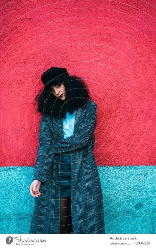Stylish curly woman at colorful wall Woman Attractive City fashionable Curly Brunette Wall (building) Multicoloured Red Bright Looking into the camera Coat