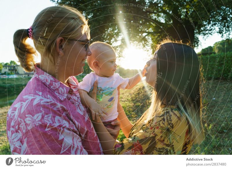 Happy lesbian couple with child Mother Child Park Green Sunbeam Human being Woman Happiness Summer Lifestyle Love same gender parents Homosexual Couple