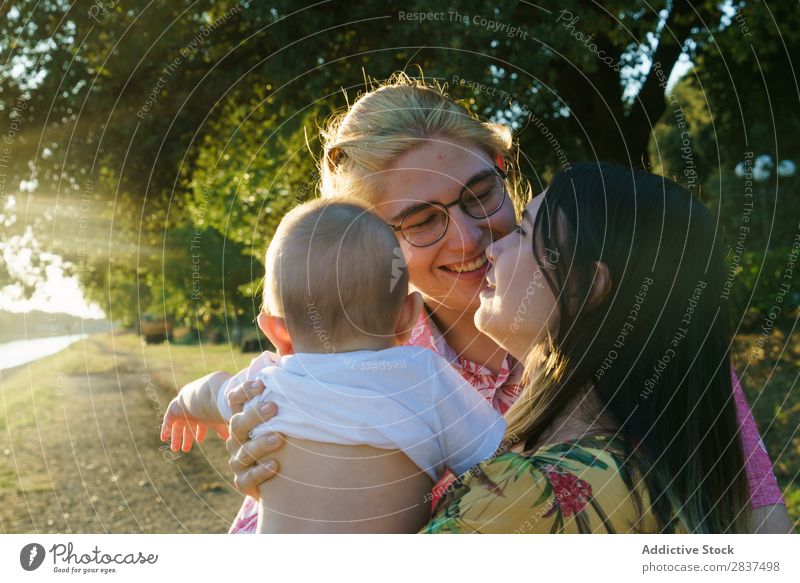 Happy lesbian couple with child Mother Child Park Green Sunbeam Human being Woman Happiness Summer Lifestyle Love same gender parents Homosexual Couple