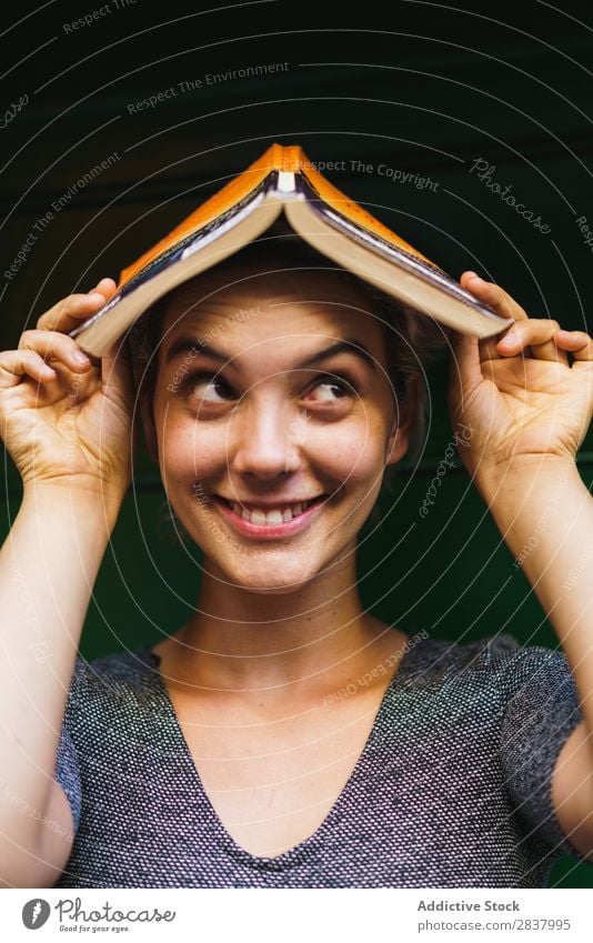 Charming girl posing with book on head Woman Book Playful Creativity having fun Happiness Cheerful enjoyment Playing Relaxation Emotions Exterior shot
