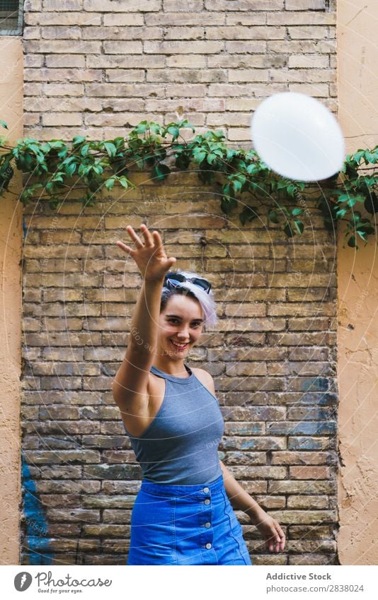Charming woman posing with balloon Woman Posture Balloon Street Easygoing Summer Emotions Happiness Feminine Brick wall Contentment Expression City Model