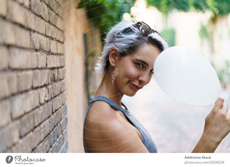 Charming woman posing with balloon Woman Posture Balloon Street Easygoing Summer Emotions Happiness Feminine Brick wall Contentment Expression City Model