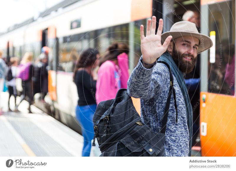 Cheerful tourist on train station Man Tourist Railroad Station Welcome Gesture Goodbye Looking into the camera Vacation & Travel Transport Trip Backpack