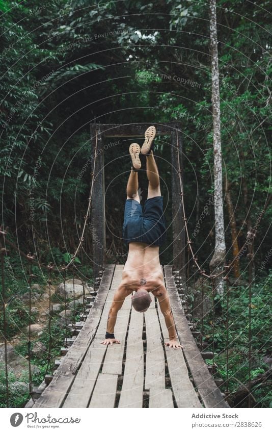 Man upside down on grungy bridge Acrobat Nature Extreme Acrobatic on hands Old shirtless Bridge Wood Healthy Lifestyle Sports Posture Adventure Strong Action