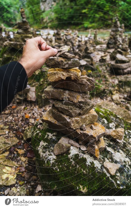 Hand building stone tower Human being Stone Tower Balance Nature Stability Stack Pebble Meditation Relaxation Rock Pyramid Zen Natural Harmonious tranquil Scene