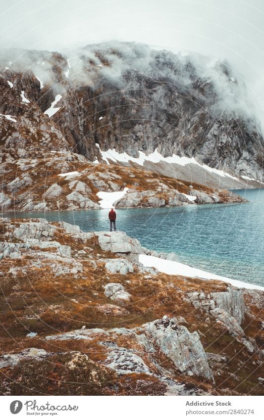 Person on rocky shore in mountains Human being Lake Mountain traveler Tourism Snow Reflection Mysterious Landscape Rock Panorama (Format) Nature Wanderlust