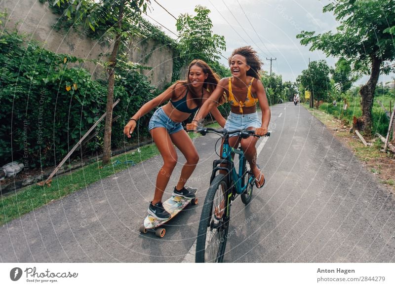 Two young woman riding bicycle and skateboard Lifestyle Sports Fitness Sports Training Bicycle Human being Feminine Young woman Youth (Young adults) 2