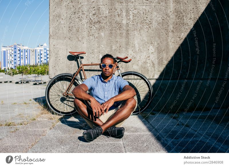 Smiling man with sunglasses sitting at bicycle Man Bicycle Sit Cycling Break Black Street Concrete Wall (building) Summer Youth (Young adults) Lifestyle City