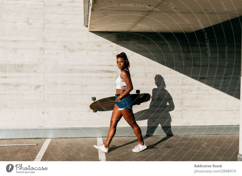 Stylish woman with board walking at street Woman Longboard Town Sports Leisure and hobbies skateboarder Black Skateboarding Youth (Young adults) African Modern