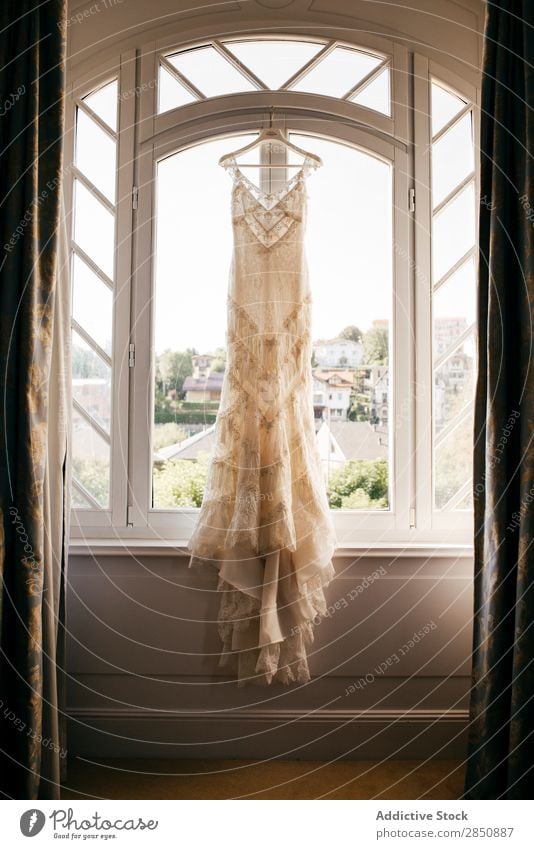 Wedding dress hanging on window - a ...