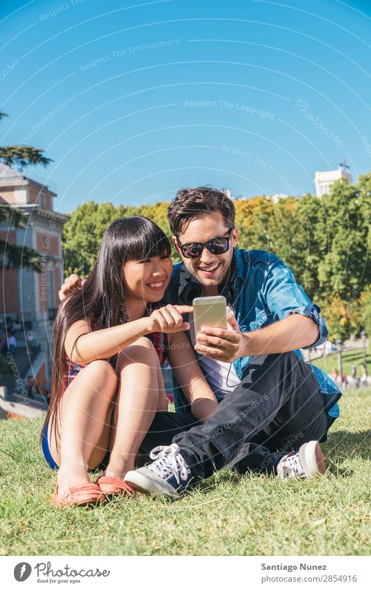 Young happy couple using smartphones in the park asian Beautiful boyfriend Easygoing Solar cell Cellphone Chinese Communication Connection Copy Space Couple