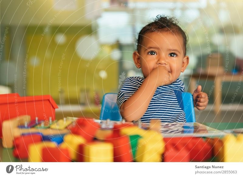 Happy baby playing with toy blocks. Baby Playing childcare mulatta multiethnic Kindergarten Portrait photograph School Toys Toddler Girl Small Child Considerate