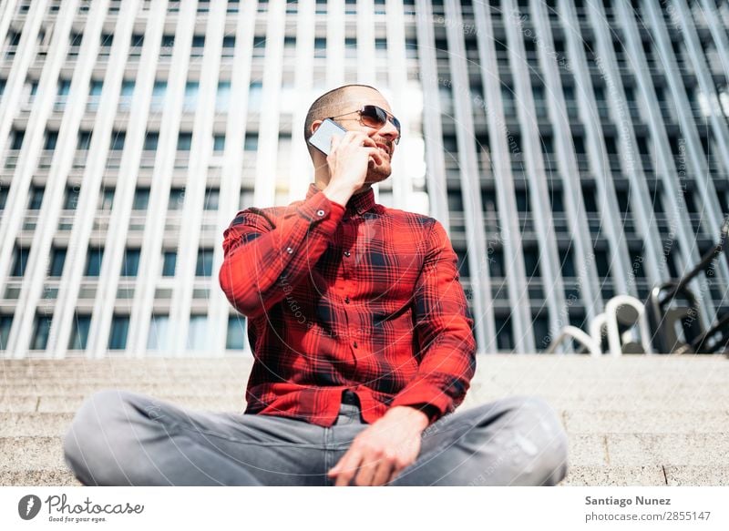 Young man with mobile phone in the city. Mobile Man Telephone Hipster Lifestyle Stand City Building Solar cell PDA Town Human being handsome Style Street