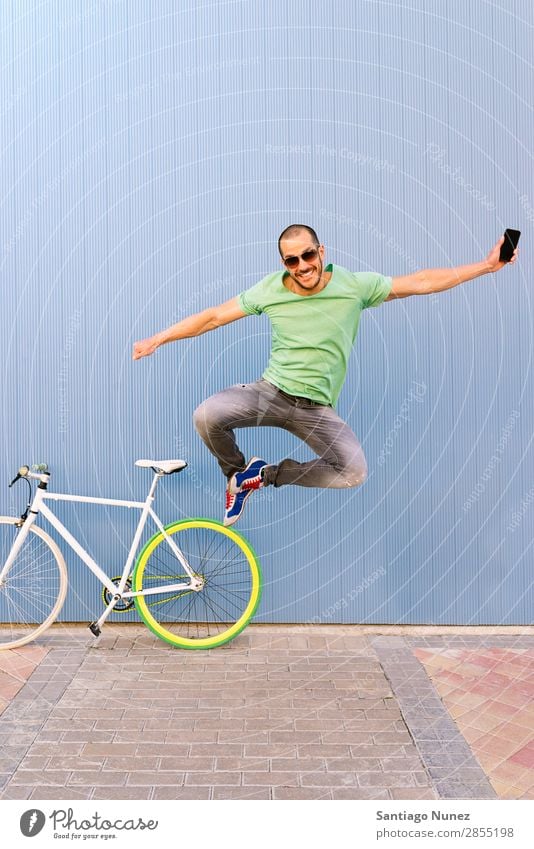 Outdoor portrait of handsome jumping. Man Jump Joy Smiling Bicycle fixie Telephone Hipster Lifestyle Stand Cycling City Town Human being Style Street PDA
