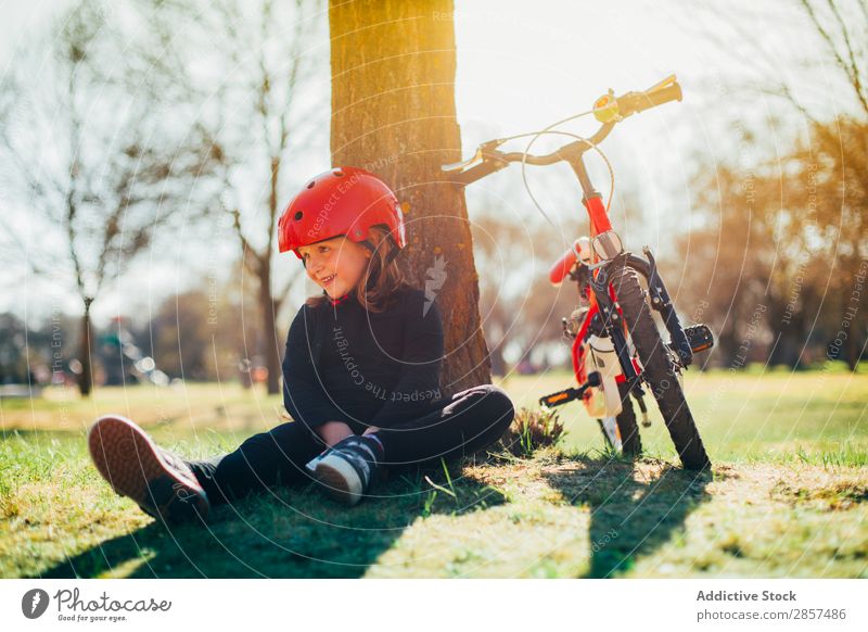 Girl resting after riding her bike Bicycle Caucasian Child Landscape Cute Joy Happy Helmet Lifestyle Exterior shot Park Sports Sunset Tree Youth (Young adults)