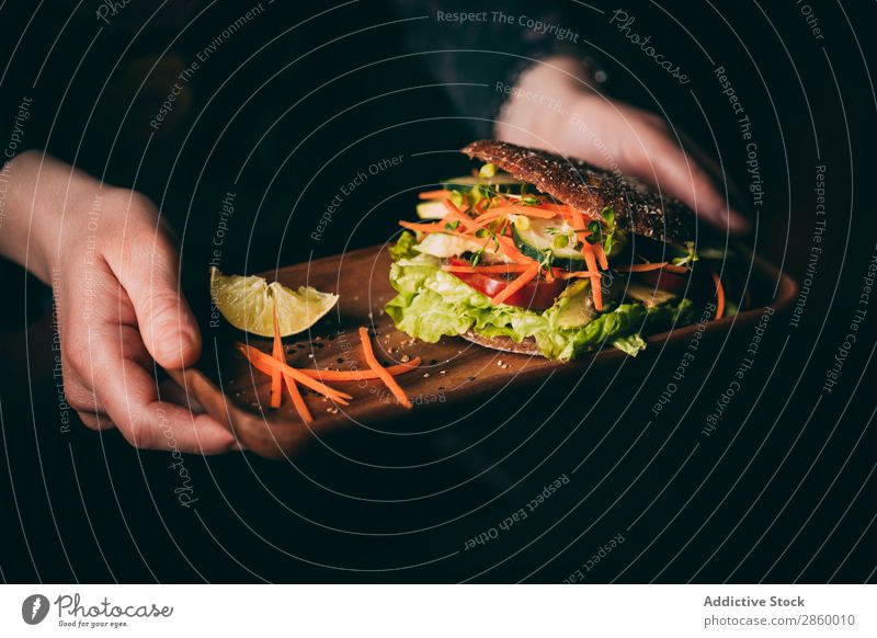 Woman holding a tray with a Vegetarian sandwich Avocado bio Bread Roll burger Carrot Cucumber Delicious Deluxe Diet eco Ecological Food Fresh Gourmet Hand