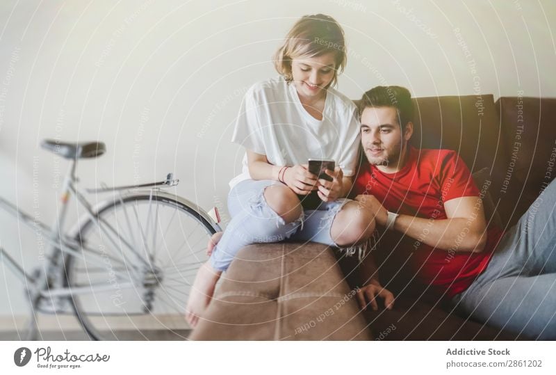Couple on sofa on the mobile phone Home Together Happy To talk interacting Smiling Coffee Love Human being Lifestyle Youth (Young adults) Easygoing Relationship