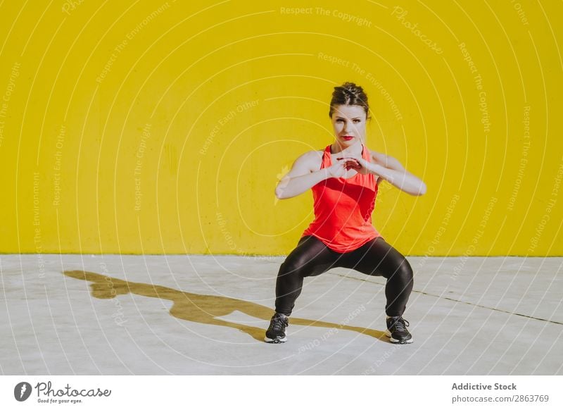 Woman doing squads exercises near a yellow wall Squad Practice Sportswear Athletic Youth (Young adults) Fitness workout Wall (building) Press Yellow Lady